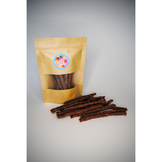 Dog treat package with treats on a grey background. Treats are meaty sticks