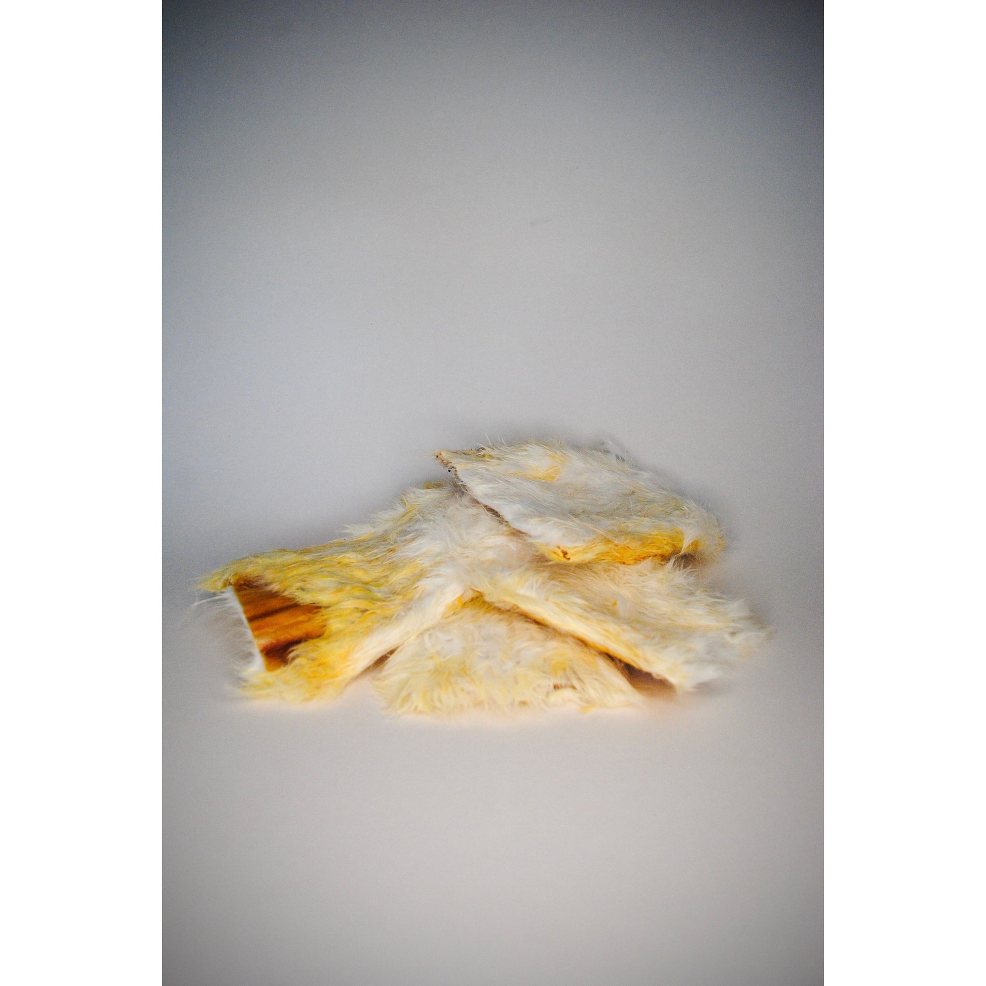 Stack of hairy dried rabbit skin, approximately 15cm on a grey background